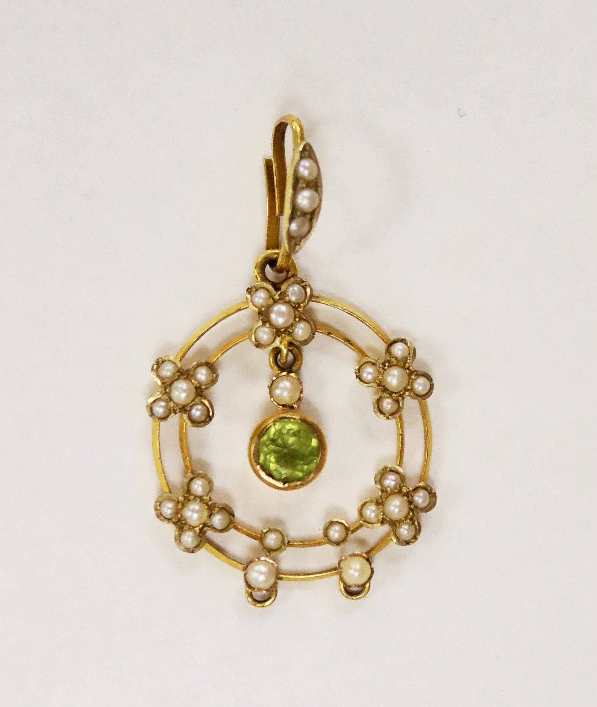 An early 20th century 9ct, peridot and seed pearl set drop pendant, overall 35mm, gross weight 2.1 grams.